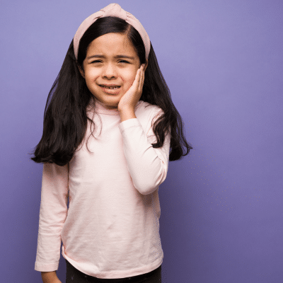 Little girl holding her jaw in pain cavities in children