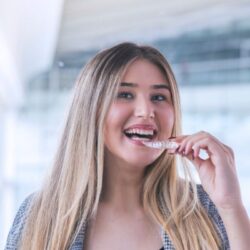 girl holding invisalign clear aligner up to her mouth