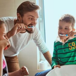 dad teaching his children how to brush their teeth