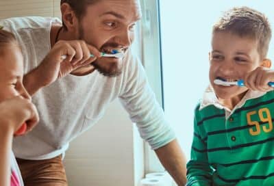 dad teaching his children how to brush their teeth
