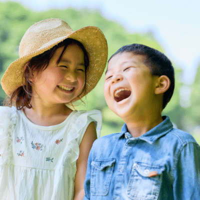 A little girl and boy laughing outside, representing childrens dental health