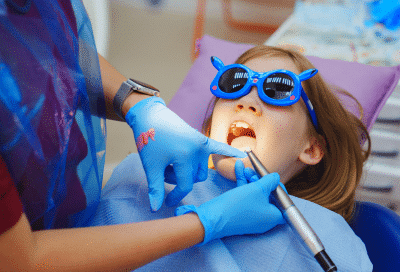 Little girl wearing blue sunglasses, getting Phase 1 orthodontic treatment