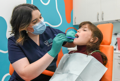 Dr. Yi gently examines a young patient during a dental visit at Richmond Pediatric Dentistry & Orthodontics, demonstrating Why National Children’s Dental Health Month Is Important for early preventive care and healthy smile development.