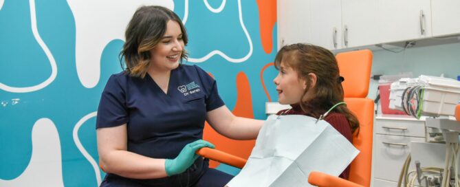 Find the Best Dentist for Kids in Richmond, VA — A pediatric dentist chats with a smiling young patient in a colorful, kid-friendly treatment room at Richmond Pediatric Dentistry and Orthodontics