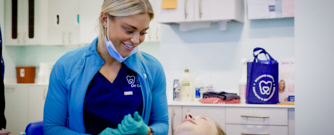 Dr. Payton Cook, orthodontist in Midlothian at Richmond Pediatric Dentistry and Orthodontics, smiling while providing orthodontic care to a young patient in the treatment chair