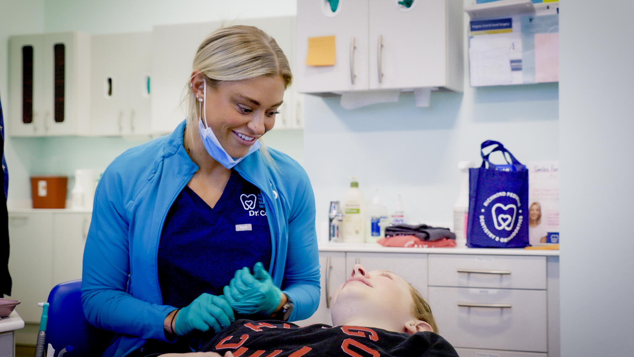 Dr. Payton Cook, orthodontist in Midlothian at Richmond Pediatric Dentistry and Orthodontics, smiling while providing orthodontic care to a young patient in the treatment chair