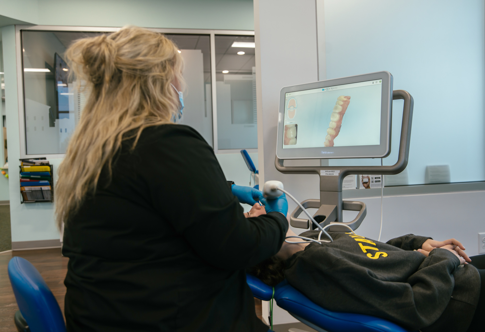 Orthodontic team member using an iTero digital scanner on a patient at Richmond Pediatric Dentistry and Orthodontics, with the live 3D scan visible on the monitorCaption