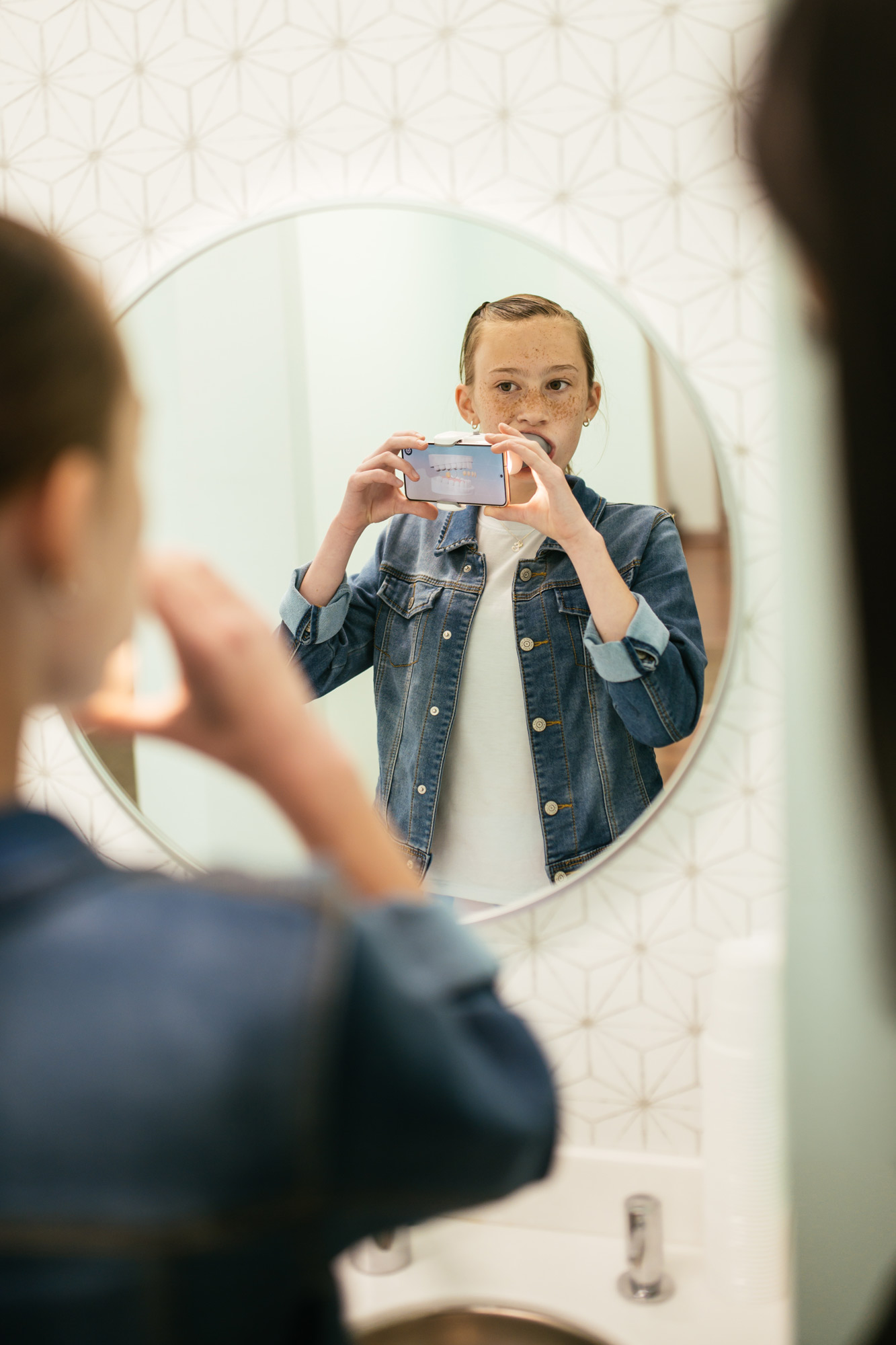 Teen orthodontic patient using the Dental Monitoring ScanBox and smartphone to take a weekly scan at home