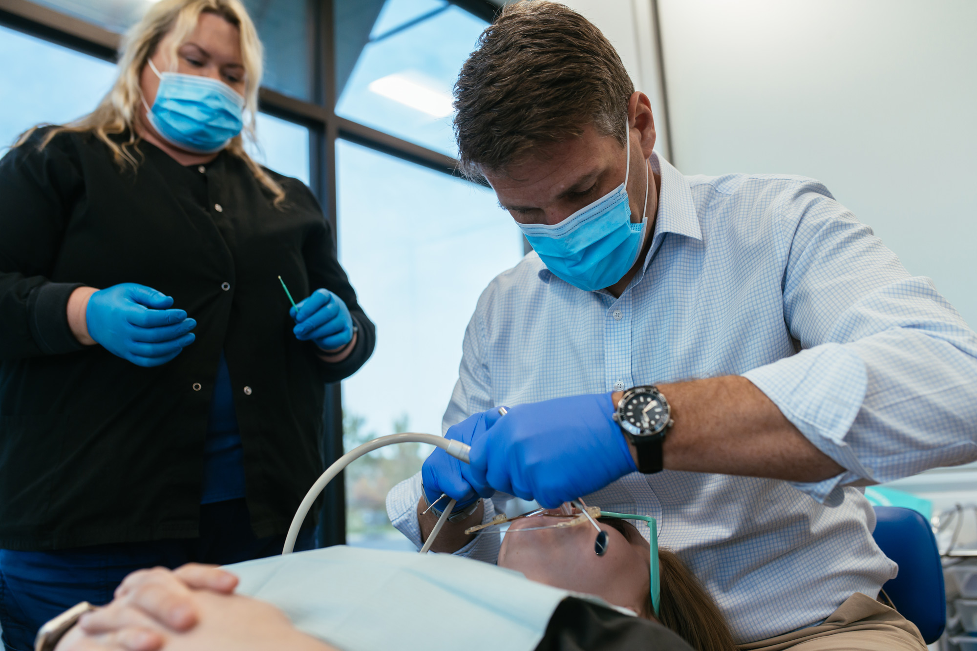 A doctor and dental assistant in masks and gloves treating a patient at Richmond Pediatric Dentistry and Orthodontics in Richmond, VA