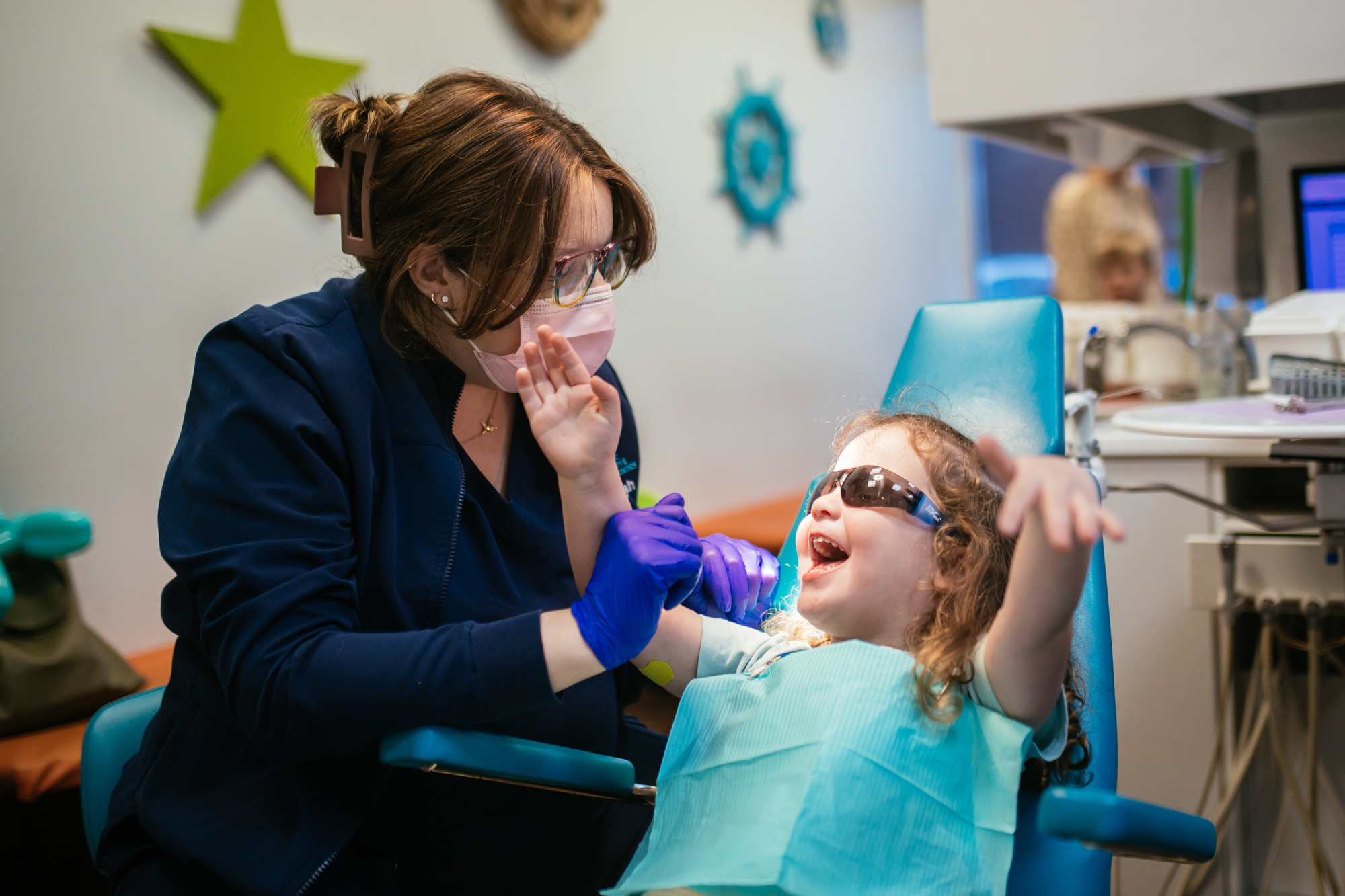 A laughing child high-fives a dental team member during a fun, stress-free visit at RPDO's Midlothian pediatric dental office