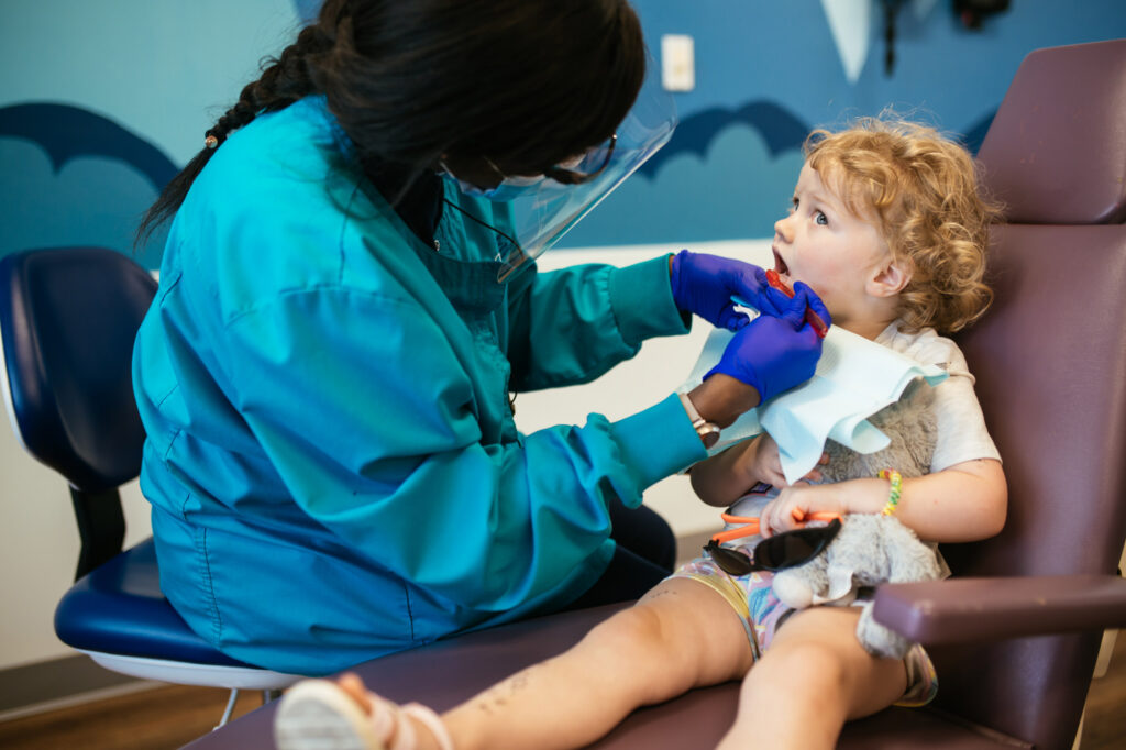 RPDO pediatric dentist showing a toddler a dental mirror during a first visit