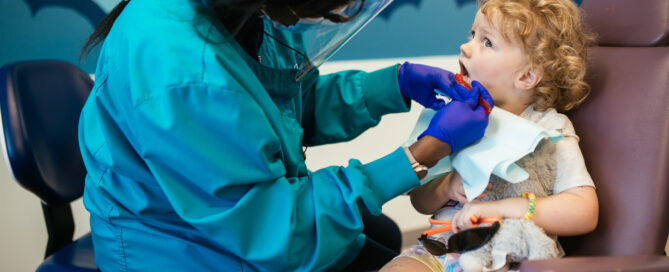 Pediatric Dentist in Short Pump, VA | RPDO 2 Pediatric dentist in Short Pump at RPDO gently examining a toddler holding a stuffed animal during a first dental visit at the Short Pump office
