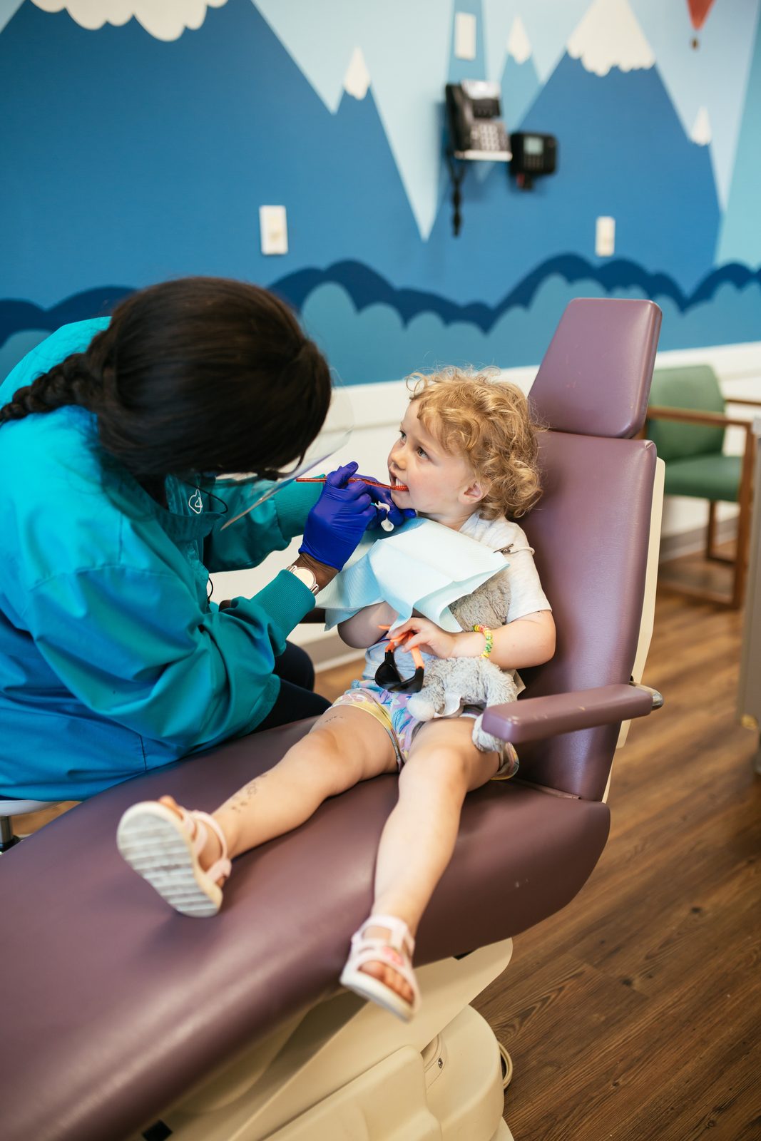 Pediatric dental team member examining a toddler holding a stuffed animal at Richmond Pediatric Dentistry and Orthodontics, a children's dentist in Henrico County, VA