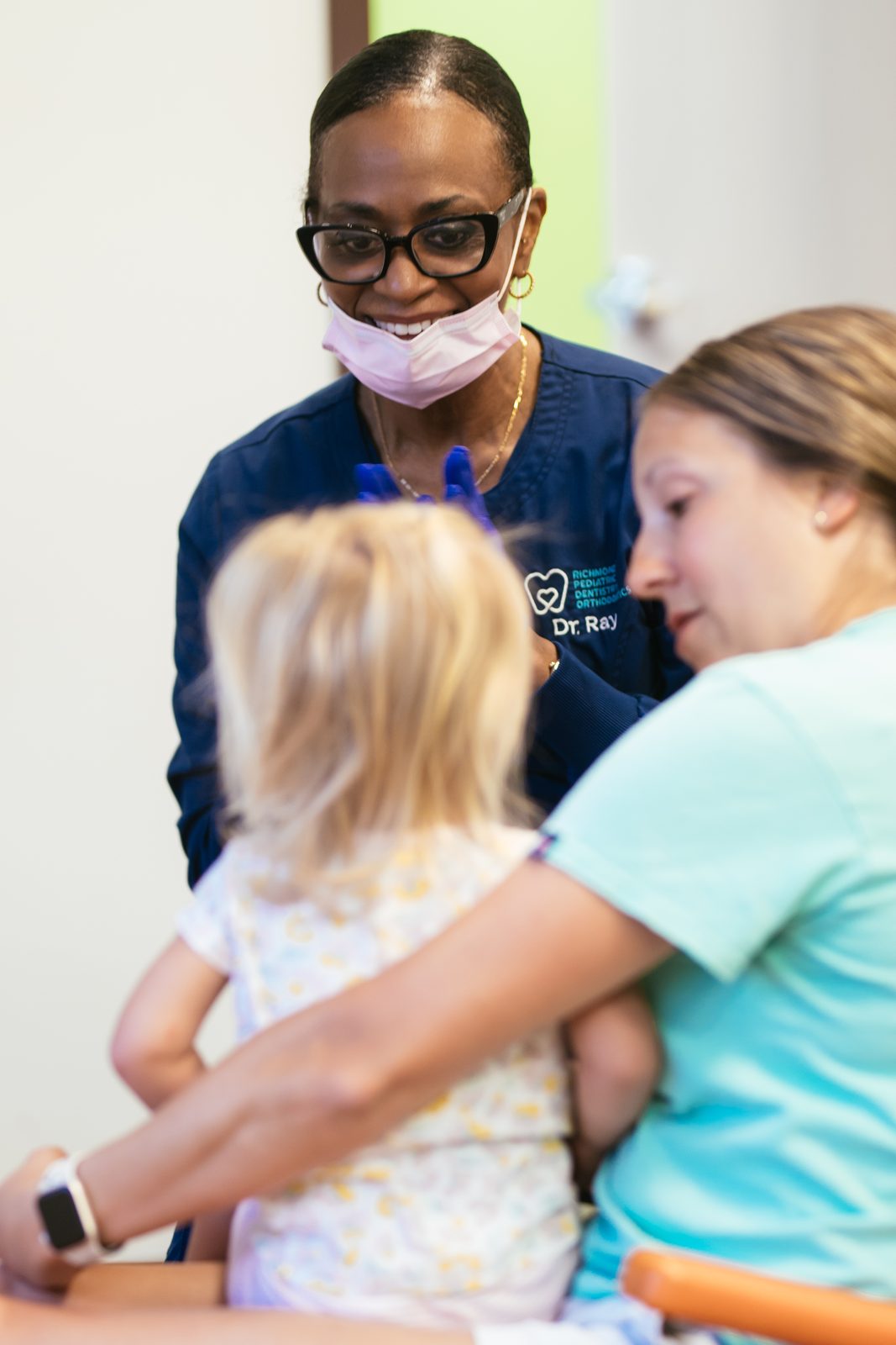 Dr. Ray greeting a young child held by their parent during a first visit at Richmond Pediatric Dentistry and Orthodontics in Henrico County, VA