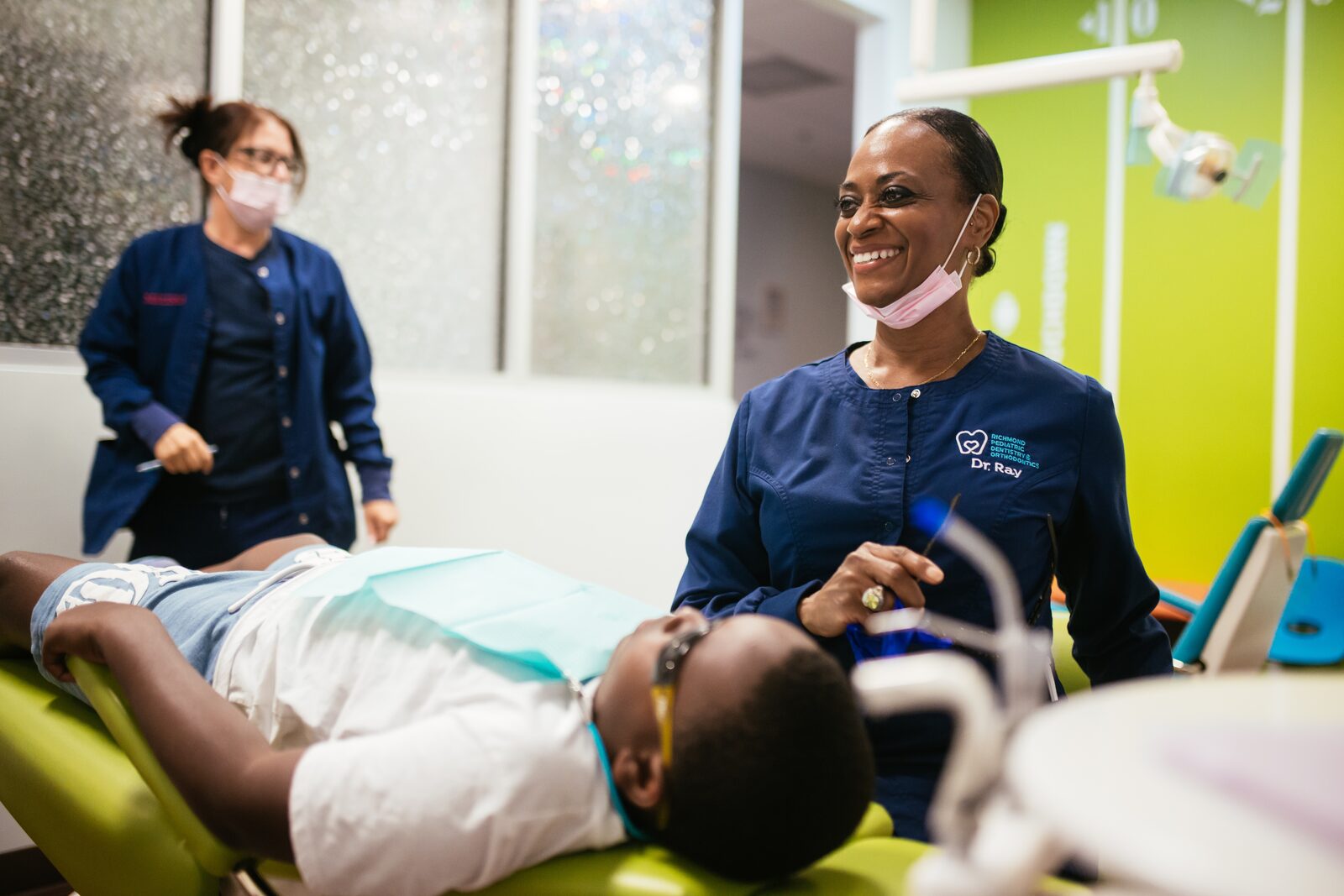Your Child’s First Visit 8 Dr. Raymonia Eddleton (Dr. Ray), pediatric dentist at RPDO in Richmond, VA, laughing with a young patient in the dental chair