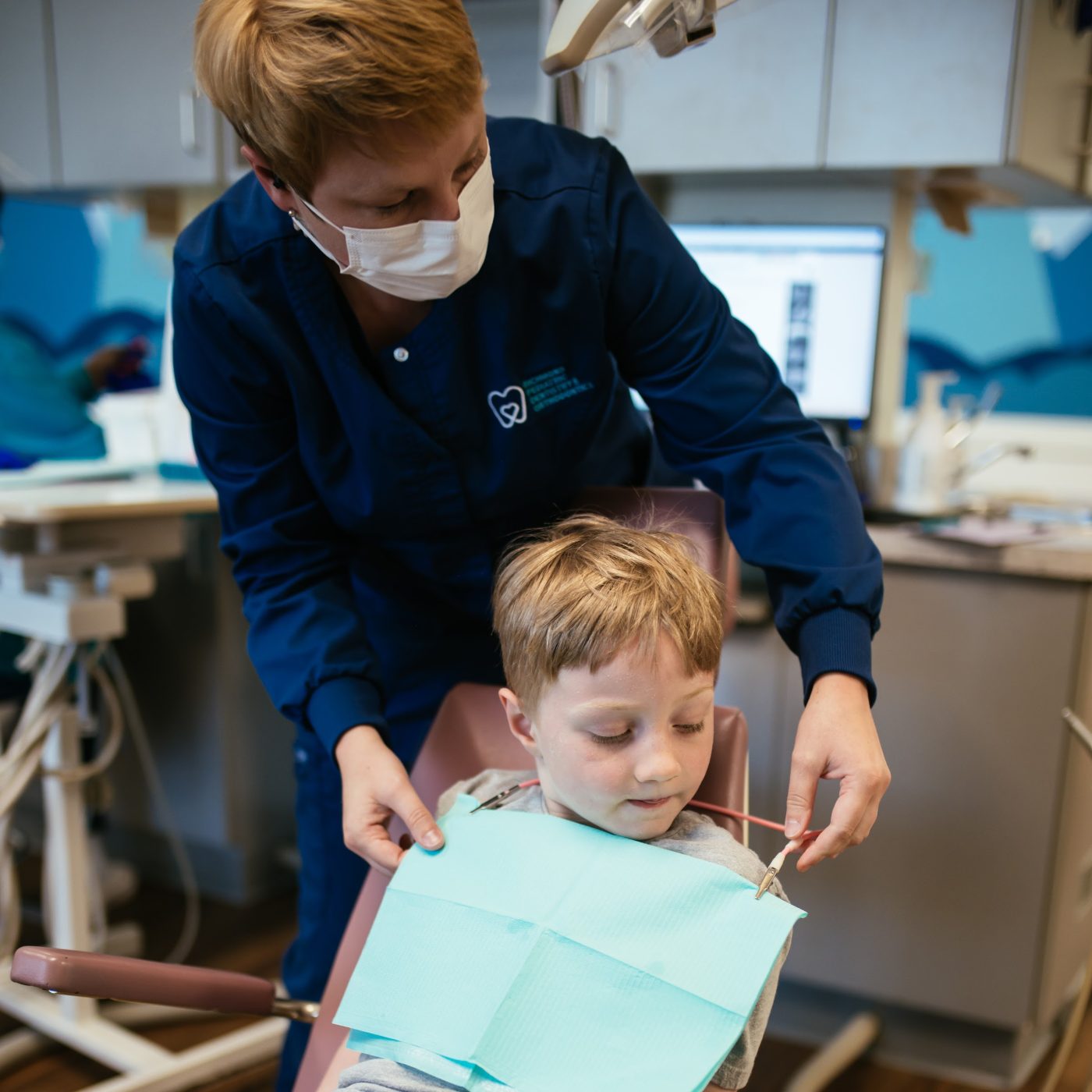 Teeth Cleaning for Kids in Richmond, VA 9 Hygienist gently putting a bib on a young boy before his teeth cleaning at RPDO in Richmond, VA