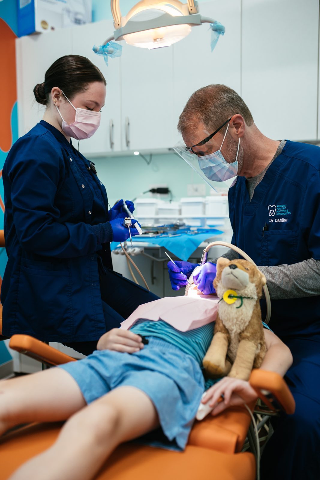 Bill Dahlke, DMD 11 Dr. Bill Dahlke and a dental assistant caring for a young patient holding a stuffed animal at Richmond Pediatric Dentistry and Orthodontics